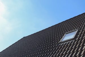 A house with black roof tile paint under a clear blue sky, highlighting the aesthetic appeal and climate suitability.