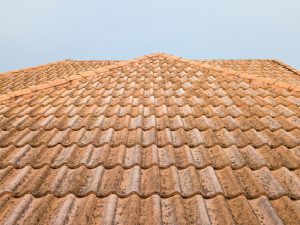 Roof restoration mistakes: Damaged terracotta roof tiles on a house.