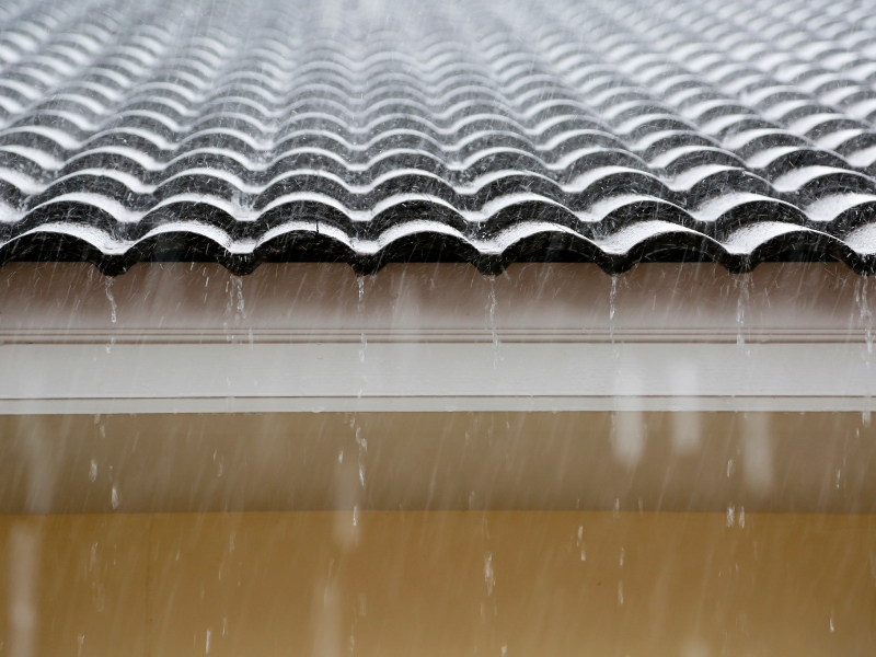Heavy rain on tiled roof showing water overflow, ideal for best roof leak repair comparison.
